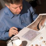 Dr. Stephen Houston examines photographs and artifacts from the Royal Tomb.