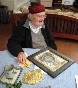 The artist reviews the gilded, sculpted prints. 