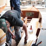 Craftsmen brush a final coat of epoxy on an 18-foot sailboat.
