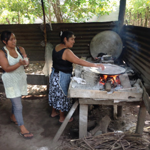 A woman uses a steel plancha over an open fire to make tortillas in the traditional method.