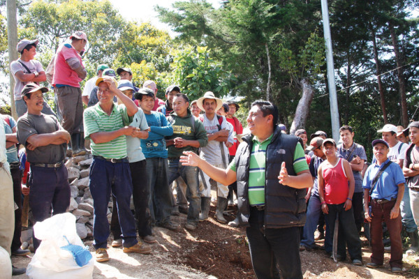 Project manager greeting workers at site of water distribution tank.